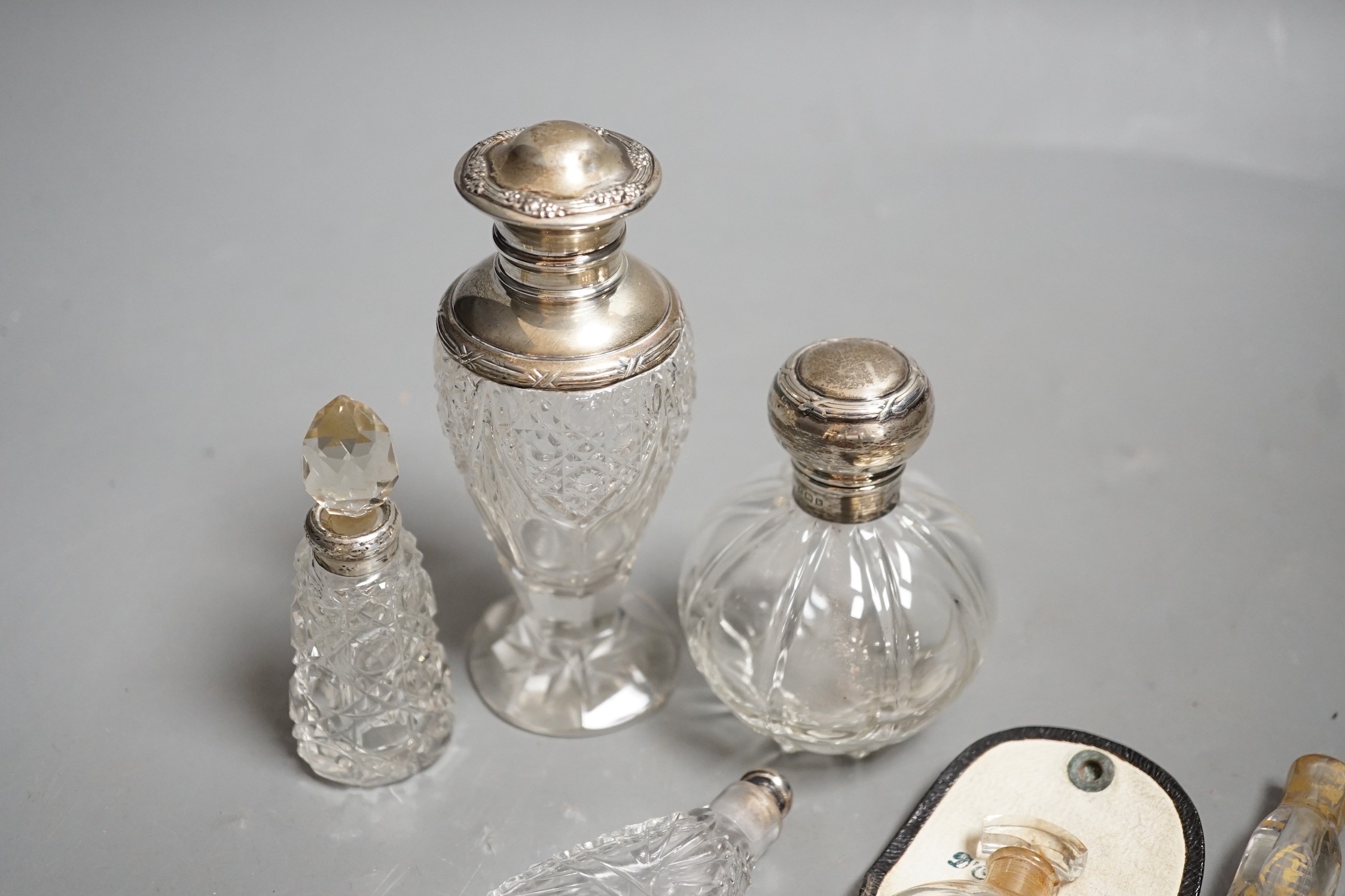 A late Victorian silver mounted ruby glass cylindrical scent bottle, engraved in the style of Kate Greenaway, Sampson Mordan & Co, London, 1887, 75mm, together with eight other assorted glass scent bottles, three with si